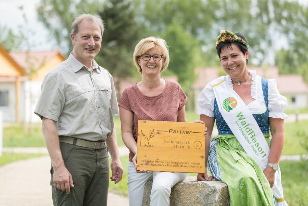Rüdiger Biehl, stellvertretender Leiter des Nationalparks Hainich, übergibt Nationalpark-Partner-Holztafel an Objektleiterin Cornelia Faske und Kräuterpädagogin Ines Mey vom WaldResort Hainich